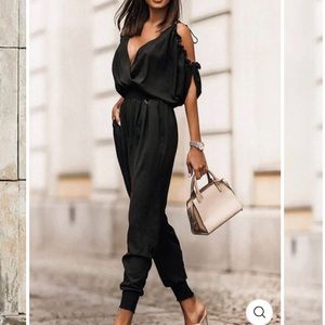 Black jumpsuit with cutout shoulder and straps.